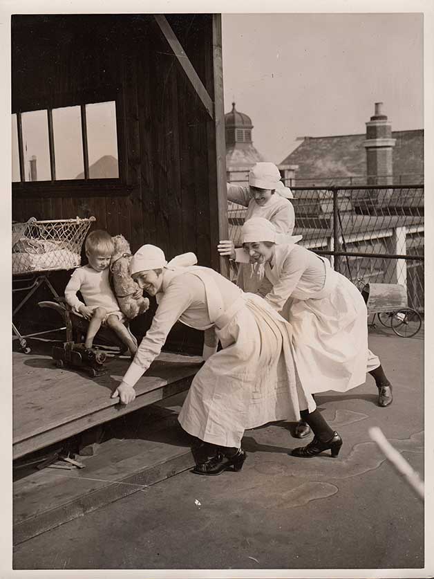 Enfermeras poniendo a los niños a tomar el sol en el West London Hospital